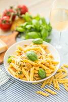 Pâtes Penne avec poulet pièces champignons basilic Parmesan fromage et blanc du vin. italien nourriture dans blanc assiette sur cuisine table photo