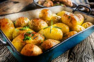 rôti patates avec herbes dans la poêle sur rustique chêne table photo