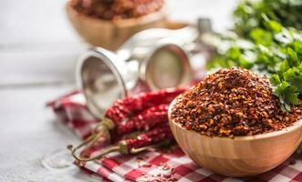 séché et écrasé le Chili poivrons dans en bois quilles avec persil herbes photo