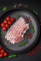 Frais brut Bacon Couper dans tranches avec sel, épices et herbes photo