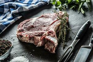 nervure œil steak avec OS sur Boucher planche avec herbes sel poivre fourchette et couteau photo