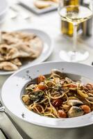 traditionnel italien spaghetti tout vongole e Pomodorini servi avec galette et blanc du vin photo