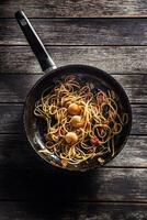 Pâtes spaghetti sur la poêle avec crevette tomate sauce toates et herbes. italien ou méditerranéen cuisine photo