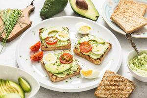 en bonne santé petit déjeuner de toasts avec Avocat propager guacamole Oeuf tomate et ciboulette. photo