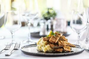 différent présentation de une traditionnel schnitzel avec Patate salade, servi sur une bien décoré restaurant table photo