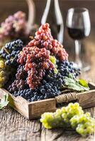 juteux grappes de les raisins dans une en bois boîte, rouge du vin dans le Contexte photo