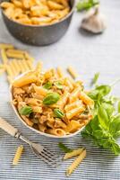 Pâtes Penne avec poulet pièces champignons basilic et Parmesan fromage italien nourriture dans blanc bol sur cuisine table photo