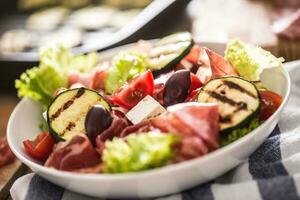 Frais salade salade avec grillé Zucchini coppa di parme jambon feta fromage Olives tomates et olive pétrole photo