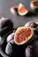 une peu figues dans une noir bol sur un foncé béton table photo