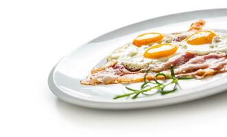 jambon et des œufs. Bacon et des œufs. salé Oeuf avec poivre sur blanc plaque. Anglais petit déjeuner photo