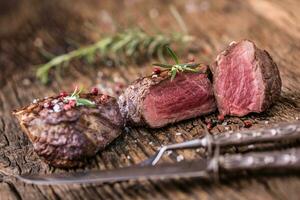 grillé du boeuf steak avec Romarin, sel et poivre sur vieux Coupe planche. du boeuf filet steak. photo