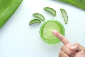 aloe vera frais tranché et gel liquide dans un récipient en plastique sur fond blanc photo