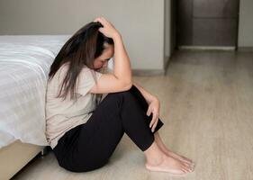 triste déprimé Asie femme Souffrance sur le blanc lit, elle est séance dans lit et émouvant sa front, sommeil désordre et stress concept photo