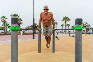 attrayant retraité homme Faire gymnastique des exercices dans un Extérieur Publique Gym à une recours photo