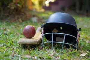 l'équipement de cricket est une balle de cricket, une batte de cricket, un casque de cricket sur fond d'herbe. mise au point douce et sélective. photo