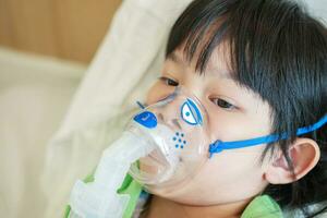 malade peu asiatique fille inhalation avec nébuliseur pour respiratoire traitement photo