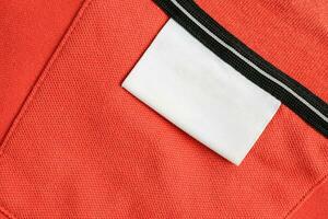 Vide blanc blanchisserie se soucier vêtements étiquette sur Orange chemise en tissu texture Contexte photo