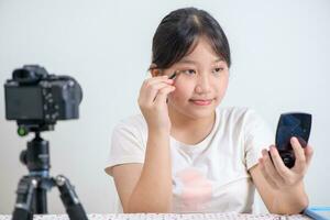 beauté fille blogueur concept, asiatique femme dessiner les sourcils la revue dans vivre diffusion isolé photo