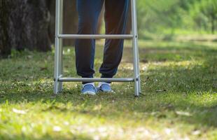 Sénior homme jambes entraine toi en marchant en dessous de le arbre dans le parc parmi le Matin Soleil concept soins de santé, maladie, espoir, santé réhabilitation photo