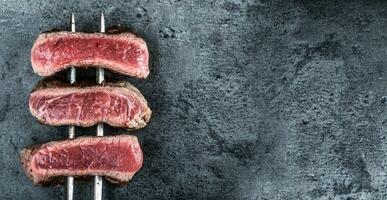 biaisé steaks de du boeuf cuit sur chaud foncé des pierres vu de le Haut photo