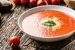 chaud tomate soupe Parmesan fromage et basilic laisser sur vieux oal table photo