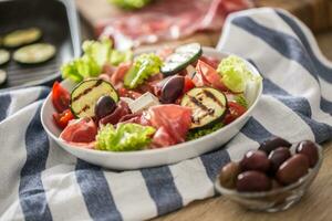 Frais salade salade avec grillé Zucchini coppa di parme jambon feta fromage Olives tomates et olive pétrole photo