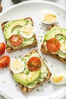 en bonne santé petit déjeuner de toasts avec Avocat propager guacamole Oeuf tomate et ciboulette. photo