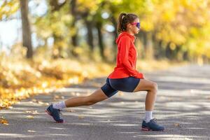 Jeune femelle athlète dans tenue de sport est chauffage en haut avant fonctionnement dans le l'automne parc photo