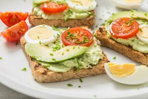 en bonne santé petit déjeuner de toasts avec Avocat propager guacamole Oeuf tomate et ciboulette. photo