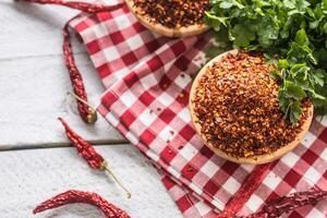 séché et écrasé le Chili poivrons dans en bois quilles avec persil herbes photo