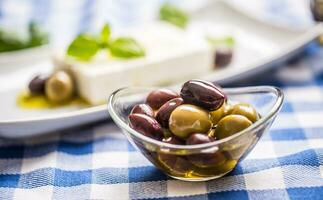 vert et rouge Olives dans bol avec olive pétrole et grec feta fromage dans le Contexte photo