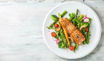 rôti Saumon steak avec asperges brocoli carotte tomates un radis vert des haricots et petits pois. poisson repas avec Frais légume photo