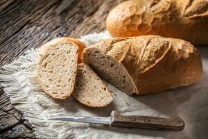 deux tranches de croustillant cuit pain sur une rustique tissu et en bois Contexte avec une couteau sur le côté photo