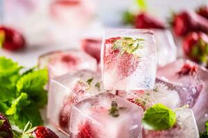 Frais des fraises congelé dans la glace blocs avec mélisse feuilles photo