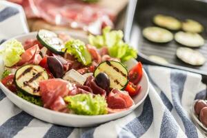 Frais salade salade avec grillé Zucchini coppa di parme jambon feta fromage Olives tomates et olive pétrole photo