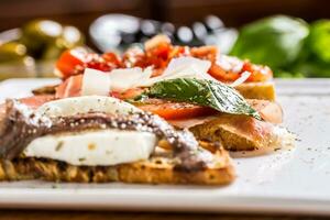 savoureux italien apéritif bruschette avec tomates anchois prosciutto et Mozarella photo