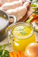 poulet bouillon dans une verre pot brut poulet jambes carotte oignon céleri herbes Ail et Frais des légumes photo