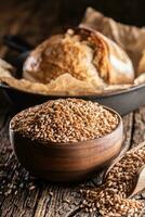 blé grains-les principale ingrédient de le pain rempli dans en bois bol et en bois rustique scoop. cuire au four croustillant pain dans le backround photo