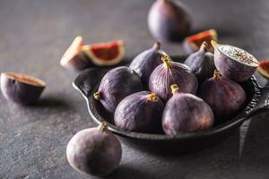 une peu figues dans une noir bol sur un foncé béton table photo