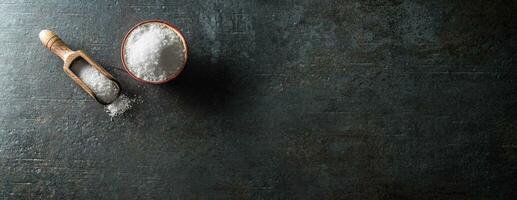 granulé sel dans une bol avec une scoop sur une béton table - panoramique bannière. photo