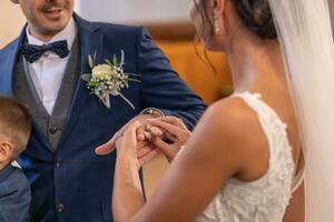 la mariée met une bague sur une doigt de une jeune marié pendant une mariage cérémonie, devenir mari et épouse photo
