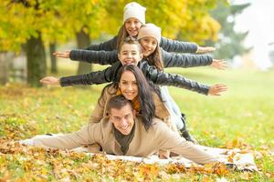 bras large ouvert de maman, papa et Trois des gamins empilé en haut en plein air pendant l'automne journée avec coloré feuilles photo