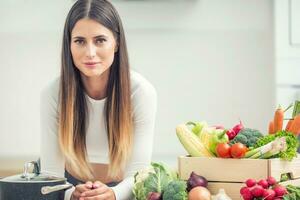 Jeune femme dans sa cuisine avec Frais biologique légume à la recherche dans le caméra photo