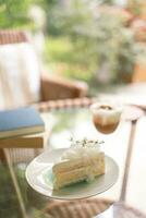 noix de coco gâteau et café dans une café sur le brouiller Contexte. traditionnel dessert tranché de délicieux noix de coco couche gâteau photo