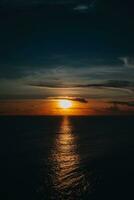 brillant Orange le coucher du soleil sur le foncé Indien océan sur bali île. soir lumière du soleil, Feu ciel, incroyable vue photo