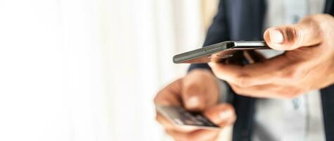 Beau homme d'affaire dans costume en portant une intelligent téléphone dans main et payant par une crédit carte dans local magasin photo