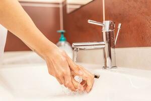 la lessive mains avec l'eau et liquide savon dans le salle de bains photo