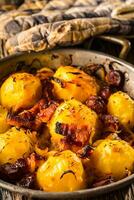patates. rôti patates avec Bacon oignon et saucisses sur vieux chêne table photo