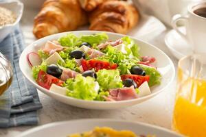 en bonne santé salade dans une bol avec Olives, radis, tomate, fromage et maigre jambon servi pour petit déjeuner photo