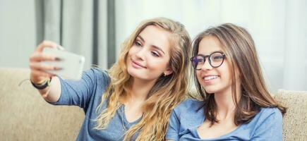 deux adolescent les filles sourire et prendre une selfie ensemble. photo